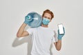 Picture of a young redhead deliveryman carrying a huge bottle of water and holding a smartphone