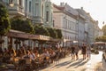 Young people walking on a pedestrian street of Szeged, Southern Hungary, with other people sitting on tables in cafes & restaurant Royalty Free Stock Photo