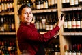 Picture of young woman with bottle in her hands in wine shop