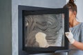 Picture of young woman cleaning fireplace glass doors