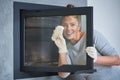 Picture of young woman cleaning fireplace glass doors