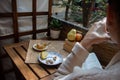 Picture of young woman enjoying quiet morning time at balcony with book and organic tea