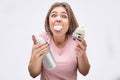 Picture of young woman with mouth full of white cream. She hold cake and cartrige. Isolated on grey background.