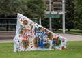 Abstract art on the back of a white stone whose front has the colors of the gay pride flag.