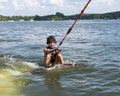 Amerasian teenage boy being pulled out of the water on a small surfboard used to surf the wake of the boat on Grand Lake. Royalty Free Stock Photo