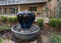 Apple shaped deep blue shiny fountain inside a rock filled basin at the Botanical Gardens at Heritage Park in Grapevine, Texas.