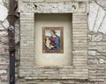 Art piece featuring the Madonna with the Child Jesus in an outside wall niche on a street in Assisi, Italy .