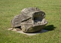 Grotesque stone ornamental figure on display in green grass in Portugal.