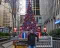 Tourist posing before a Christmas display with tree, gifts and Nutcrackers in Fox Square on 6th Avenue in New York City