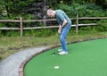 75 year-old man playing miniature golf on a family vacation in Bar Harbor, Maine. Royalty Free Stock Photo