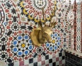 Closeup of a mosaic fountain with geometric Arabic design and stag head faucet on display at Art Naji in Fez, Morocco. Royalty Free Stock Photo