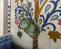 Closeup of a mosaic fountain with geometric Arabic design and stag head faucet on display at Art Naji in Fez, Morocco.