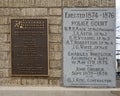 Closeup of an information plaque of engraved stone in a brick wall of the old Commissioner`s Court Building in McKinney, Texas.