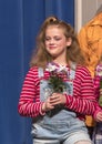 Eleven-year old girl standing holding flowers on stage in school play