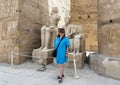 Tourist before statue of the god Amun-Re and his wife Mut and a seated king just before the Colonnade Hall in Luxor Temple. Royalty Free Stock Photo