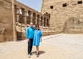 Tourist couple and row of ram-headed sphinxes in front of a row of columns in the first courtyard of the Temple of Amun.