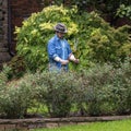 Hyperrealistic sculpture of a man clipping hedges in yard in Highland Park, Dallas.