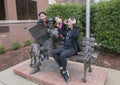 Family posing humorously with bronze of Will Rogers on a bench, Claremore, Oklahoma Royalty Free Stock Photo