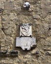 Pictured is a relief of a lion in rampant position on shield above another artifact on a stone wall in San Gimignano, Italy.