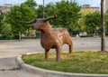 Metal steel sculpture of a bull standing in a grass island in a parking lot in Dallas, Texas.