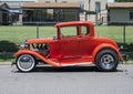 Orange 1929 Ford Model A Coupe restored with racing tires and engine parked on a residential street in Dallas, Texas.