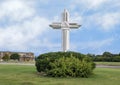 Ornate white wooden cross surrounded by green bushes in Plano, Texas.