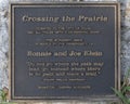 Plaque by the bronze sculpture titled Crossing the Prairie by Glenna Goodacre along the Tulsa River Trail in Oklahoma.