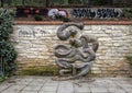 Snake sculpture on stone wall, with grafitti in background, Lesser Town, Prague, Czech Republic