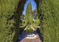 Round fountains, manicured hedges and giant trees, other plants and walkways in the gardens of the Alhambra in Granada, Spain.