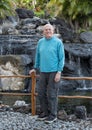 Seventy-three year-old caucasian male tourist posing in front of a man made waterfall at a resort on the Big Island, Hawaii.