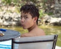 Thirteen year old Amerasian boy looking back over his left shoulder on a dock chair in Grand Lake in the State of Oklahoma