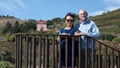 Female Korean tourist and husband on a viewpoint in the River Douro Valley in Portugal, with a landscape in the background.