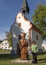 Korean woman and wooden sculpture St. John of Nepomuk with small chapel, The Village of Holasovice, Czech Republic Royalty Free Stock Photo