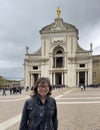 Smiling female Korean tourist in front of the Basilica of Saint Mary of the Angels just outside Assisi, Italy.