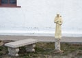 Bench and statue of a saint holding a crucifix with a dove on his left shoulder at Saint Joseph Catholic Church in Fort Davis