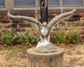Stone sculpture of an eagle with outstretched wings on a concrete pedestal at the base of a flagpole in Edmond, Oklahoma.