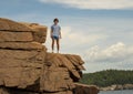 Teenage boy standing high on rugged rocks near Thunder Hole in Bar Harbor, Maine. Royalty Free Stock Photo