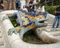 Mosaic dragon fountain and white tiled staircase at entrance to Park Guell in Barcelona, Spain..