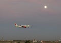 Viva Airlines jet landing in the evening with the moon in the background at Love Field in Dallas, Texas.