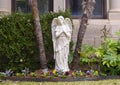 Angel statue flanked by tree trunks in the front garden of a home in Highland Park, Texas