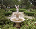White fountain with a sculpture of a young boy holding a bird in a garden at the Hill and Gilstrap Law Firm in Arlington, Texas.