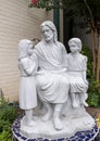 White stone statue of Saint Joseph and two children on a blue tile base at Saint Joseph Catholic School in Arlington, Texas.