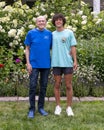 75 year-old Caucasian grandfather and his teenage grandson posing in front of a bed of beautiful flowers in Bar Harbor.