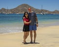 Husband and wife standing in the sand of Medano Beach with the Sea of Cortez and moored boats in the background in Cabo San Lucas. Royalty Free Stock Photo