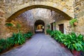 Picturesque alley with stone houses and arched passageway with green plants on the ground, Monells, Girona, Spain. Royalty Free Stock Photo