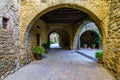 Picturesque alley with stone houses and arched passageway with green plants on the ground, Monells, Girona, Spain. Royalty Free Stock Photo
