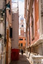Picturesque alleyway with ancient buildings and a tower in the middle, Venice, Italy.