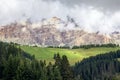 Picturesque alpine meadow at the foot of the Dolomites covered with clouds.