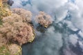 Picturesque autumn lake landscape. small island with bare trees on calm water surface with clouds reflections. aerial top view Royalty Free Stock Photo