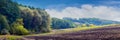 Picturesque autumn landscape with plowed field near the forest and blue sky with white clouds. Banner Royalty Free Stock Photo